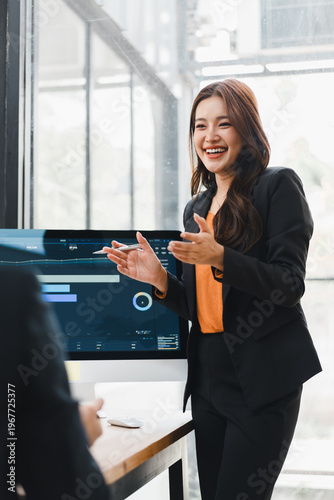 Asian businesswoman presenting data on a computer screen in a modern office