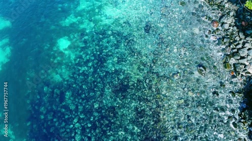 海底が見える穏やかな波打ち際を俯瞰で空撮