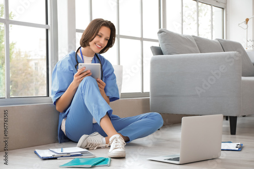 Female medical intern studying with tablet computer and laptop in clinic