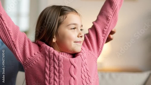 Little girl in pink sweater smiling.