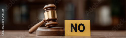 Gavel and the Decision: A gavel rests on its block beside a block displaying the word 'NO', symbolizing a definitive choice or legal ruling, set against a blurred background.