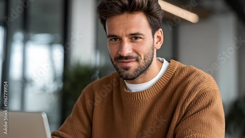 Smiling man working on laptop computer.