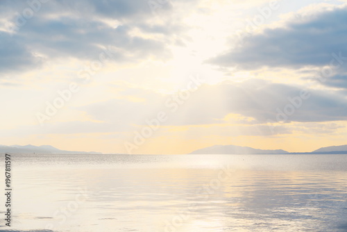 夕焼けの湖と山並み、静穏な水面に映る光の帯