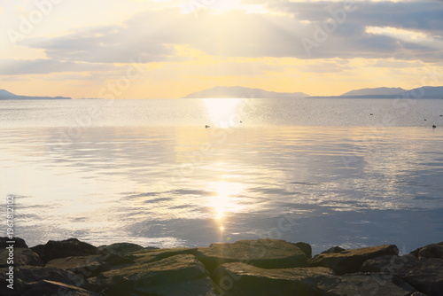 宍道湖の静穏な水面と朝日の光芒、遠景の山々