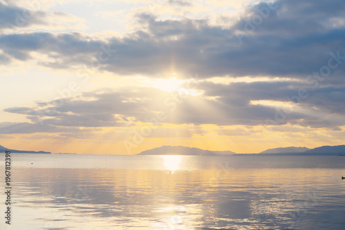 宍道湖の穏やかな湖面に映る夕焼けと灯台のシルエット