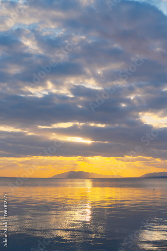 黄金の光芒、山々を照らす水平線と水面の波紋