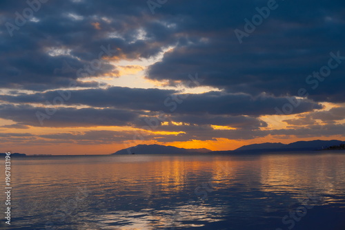 水平線に沈む夕日と水面の反射 - 幻想的な湖辺の風景
