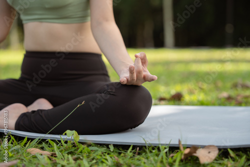 Close up Woman practicing meditating on yoga mat outdoors. Lotus pose. Yoga for health, health and wellness concept.