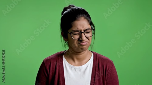 Young woman making a face of disgust or disgusted reaction against green background