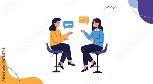 Two professional women sitting on tall stools having an engaged conversation with speech bubbles in a stylishly designed social space.
