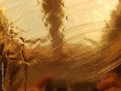 Close-up view of a crumpled, reflective golden foil surface with intricate textures and shimmering light.