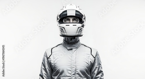 Racing driver in white helmet and suit against neutral background
