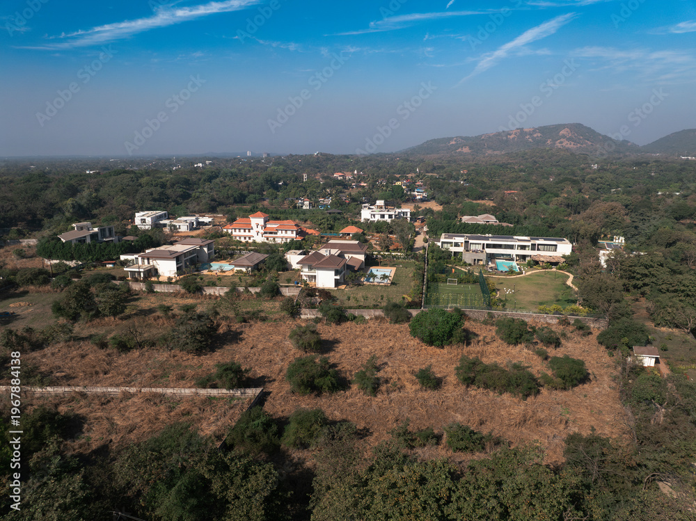 Obraz premium Stunning aerial view of a remote mountain village nestled in the hills, surrounded by beautifully layered terraced fields. The warm golden sunlight highlights the natural contours of the landscape.