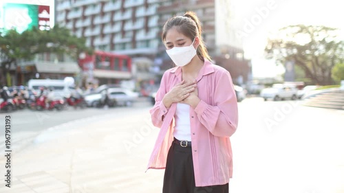 Person wearing mask in toxic urban air, monitoring pollution levels on device, highlighting health risks, environmental hazards, smog, and city pollution concerns.
