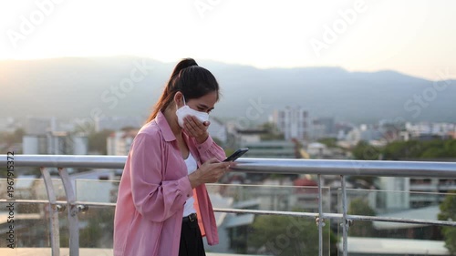 Person wearing mask in toxic urban air, monitoring pollution levels on device, highlighting health risks, environmental hazards, smog, and city pollution concerns.
