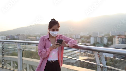 Person wearing mask in toxic urban air, monitoring pollution levels on device, highlighting health risks, environmental hazards, smog, and city pollution concerns.

