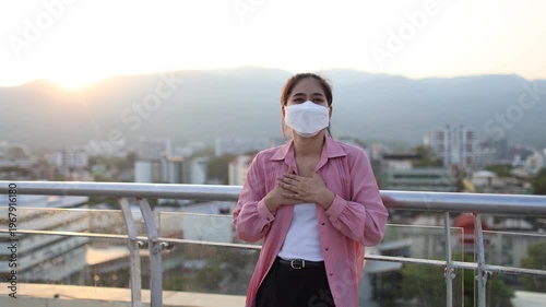 Person wearing mask in toxic urban air, monitoring pollution levels on device, highlighting health risks, environmental hazards, smog, and city pollution concerns.
