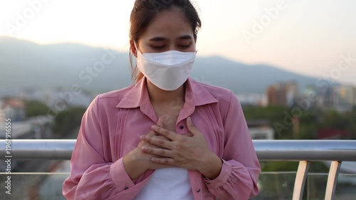 Person wearing mask in toxic urban air, monitoring pollution levels on device, highlighting health risks, environmental hazards, smog, and city pollution concerns.
