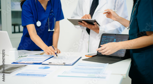 Doctors and nurses analyzing x-ray image on tablet for diagnosis, using digital technology in modern hospital, teamwork