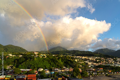 Fotografía Bright rainbow appears beneath billowing clouds over Dominica's countryside