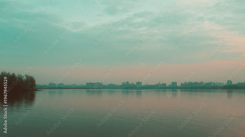 Naklejka premium Sunset over urban skyline reflected in calm water