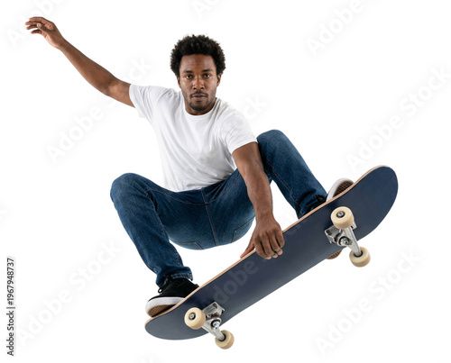 Young African American man in white t-shirt and jeans performing skateboard trick, mid-air jump, isolated on white