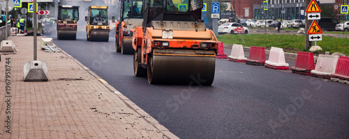 Tableau sur toile Workers operate heavy machinery to pave asphalt on a city street