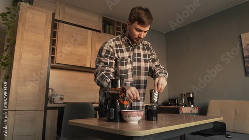 A male householder in the kitchen demonstrates attachments for a manual vegetable slicer.