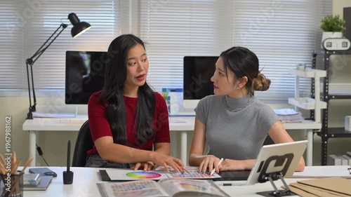 Close up of two young women hands discussing color palette and graphic design samples, creative teamwork and planning process in office..