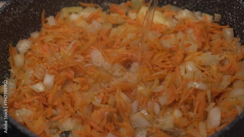 Add water to the stewed carrots and onions. Stewing vegetables in a pan.