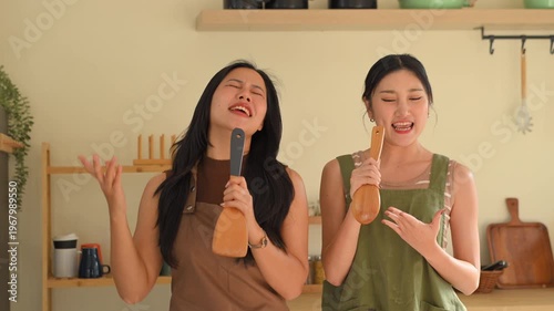Happy couple woman dancing while preparing healthy breakfast in a cozy kitchen, enjoying morning routine.
