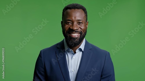 Confident professional man smiling in business suit against green background