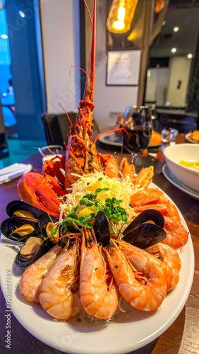 A gourmet seafood platter with a lobster centerpiece, shrimp, mussels, and garnishes, viewed on a table