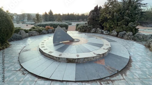Wallpaper Mural A monumental sundial sits in a peaceful, frost-covered garden surrounded by dense evergreens. The cool morning air and stone architecture create a feeling of timeless calm and solitude Torontodigital.ca