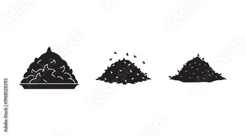 Three piles of dark material one in a tray and two heaps on the ground with some pieces falling off isolated on white background