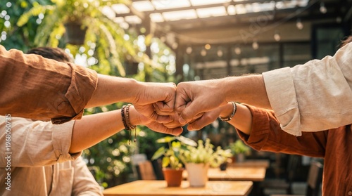 Photos Close-up of a diverse group of friends or colleagues celebrating success with a fist bump in bright sunlight outdoors