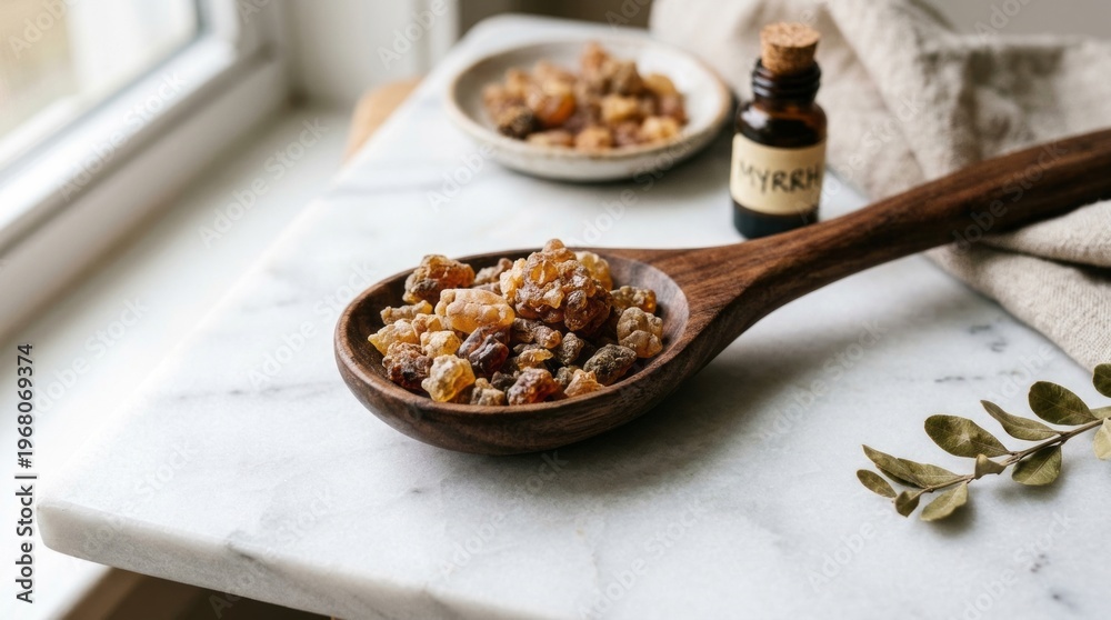 Fototapeta premium Natural resin crystals on a wooden spoon, with essential oil bottle nearby, highlighting aromatherapy ingredients.