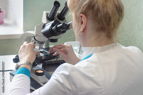 Fotografie A scientist examines a tick specimen under a microscope in a laboratory