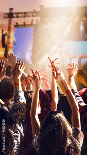Fotografie Crowd raising hands at music festival stage with bright sunlight and atmospheric haze