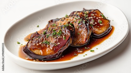 Deliciously Glazed Eggplant Slices Served on a White Plate with Garnish of Chives and Crushed Nuts for a Flavorful Asian-Inspired Dish