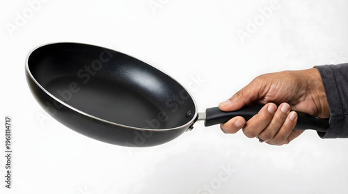 A hand holding a black frying pan with a sleek design on a white background