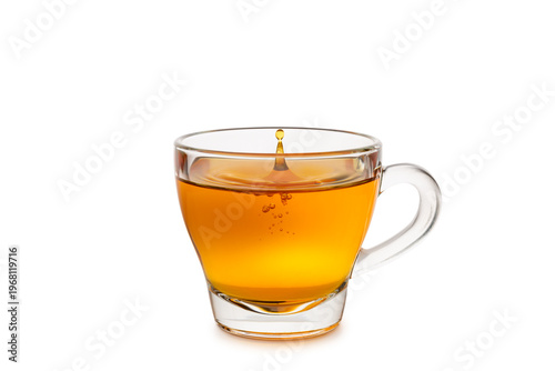 Glass cup of tea with splashing droplet isolated on white background.