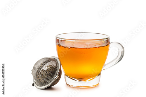 Glass cup of tea with metal tea infuser isolated on white background.