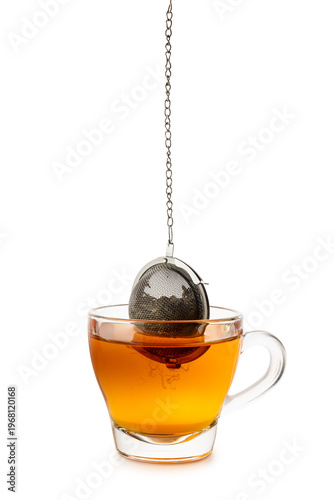 Glass cup of tea with metal tea infuser inside, isolated on white background.