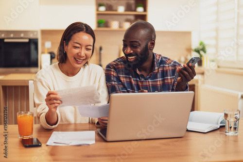 Multiracial couple doing home budget accountancy. They are discussing their expenses.
