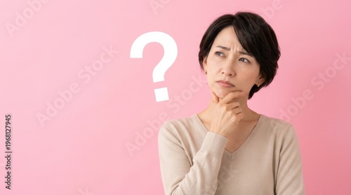 Thoughtful Asian woman pondering a difficult question with a large question mark on a vibrant pink background, symbolizing uncertainty, challenges, and decision-making.