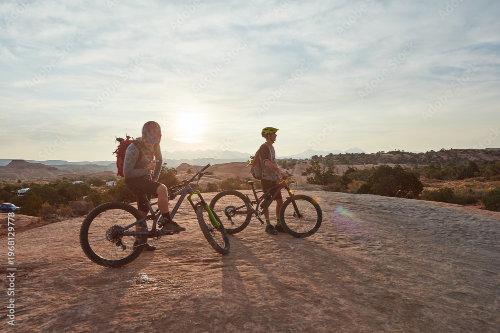 Fototapeta premium Man, friends and mountain bike with rest at sunset for break, perspective or outdoor for fitness. People, bicycle and space in sky for view in summer for exercise, wellness and cycling in countryside