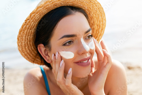 Beautiful Woman Applying Sunscreen On Cheeks At Beach Wearing Straw Hat. Sun Protection. Skincare And Body Care Concept
