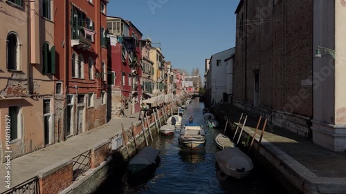 Sunny day on a quiet Venetian canal with boats