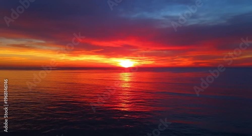 Crimson And Gold Hues Paint The Sky As The Sun Sets Over The Ocean Horizon